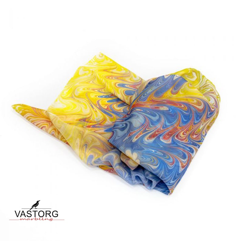 May include: A yellow and blue marbled silk scarf with red and white accents. The scarf is folded and tied in a knot.
