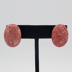May include: A pair of oval-shaped earrings with a red and white marbled pattern.