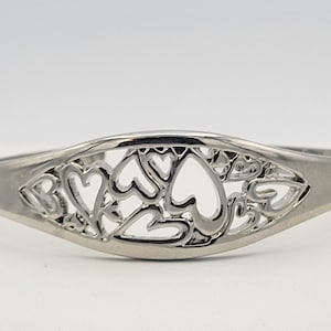 May include: A silver bangle bracelet with a delicate design of cutout hearts.