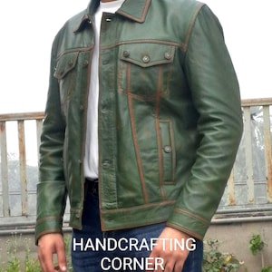 May include: A green leather jacket with brown stitching and a button closure. The jacket has a distressed look and features a pocket on the chest.