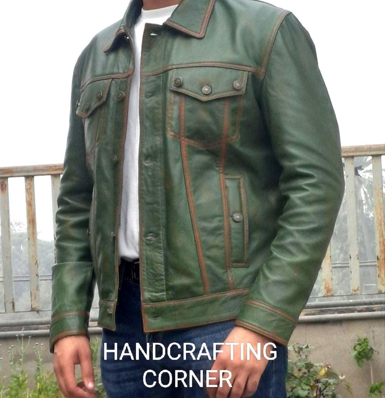 May include: A green leather jacket with brown stitching and a button closure. The jacket has a distressed look and features a pocket on the chest.