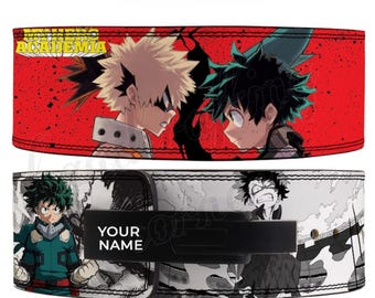 Puede incluir: Dos cinturones de halterofilia con gráficos de estilo anime. El cinturón superior presenta dos personajes sobre un fondo rojo con el texto "ACADEMIA". El cinturón inferior tiene un diseño en blanco y negro con el texto "YOUR NAME".