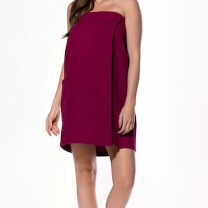 May include: A burgundy wrap-style bathrobe with a single pocket on the left side. The robe is made of a soft, absorbent material and is perfect for lounging around the house after a bath or shower.