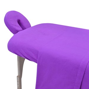 May include: Purple massage table with a matching purple headrest. The table is made of a soft, plush material and is perfect for relaxing and getting a massage.