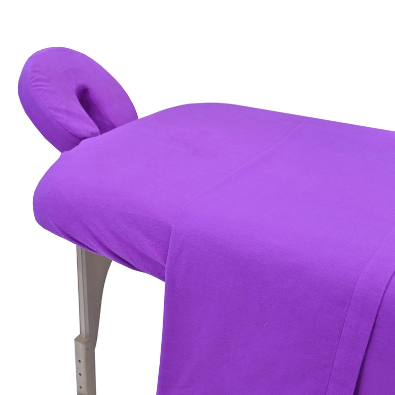 May include: Purple massage table with a matching purple headrest. The table is made of a soft, plush material and is perfect for relaxing and getting a massage.