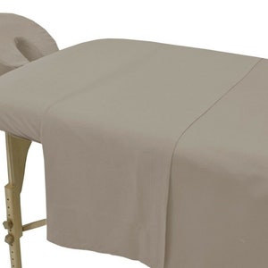 May include: A light brown massage table with a fitted sheet and a matching face cradle.