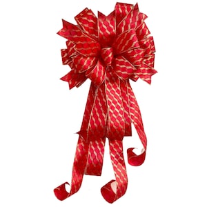 May include: A large red bow with gold glitter accents. The bow is made of wired ribbon and has a long tail.