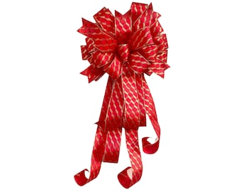 May include: A large red bow with gold glitter accents. The bow is made of wired ribbon and has a long tail.