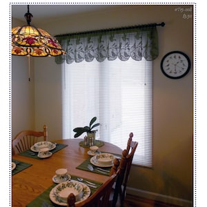 May include: A green crochet window valance featuring a repeating bird pattern with a scalloped bottom edge, hung on a black curtain rod above a window with white horizontal blinds. The text "Whimsical Birds Valance" and "Kathryn Clark Crochet" appear.