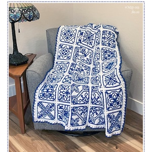 以下が含まれることがあります： 幾何学的なタイル模様の青と白のかぎ針編みブランケットが、灰色の椅子に掛けられています。ブランケットは、花柄と幾何学模様の繰り返しデザインが特徴です。「Azulejos Tiles」というテキストが画像の上部にあります。