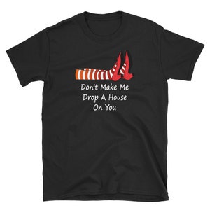 Könnte beinhalten: Schwarzes T-Shirt mit rot-weiß gestreiften Hexenbeinen und dem Text "Lass mich nicht ein Haus auf dich fallen lassen".