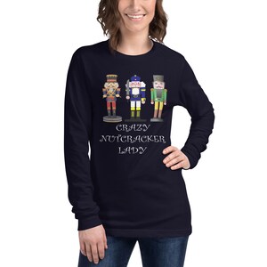 May include: A navy blue long-sleeved t-shirt with a graphic of three nutcracker figurines and the text "Crazy Nutcracker Lady".