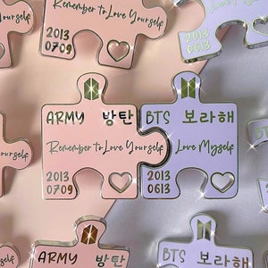 May include: Two pink and purple puzzle pieces that fit together. The pink piece says "ARMY 방탄 Remember to Love Yourself" and the purple piece says "BTS 보라해 Love Myself". Both pieces have a heart shape in the middle and the year 2013 with the numbers 0709 and 0613.
