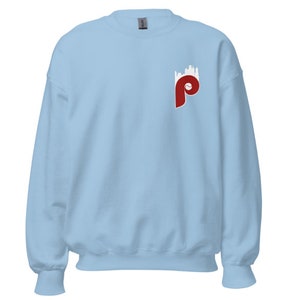 May include: A light blue sweatshirt with a red Philadelphia Phillies logo on the left chest. The logo features a stylised "P" with a baseball inside and a white city skyline behind it.