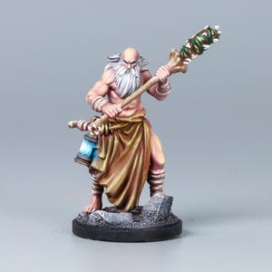 May include: A painted miniature figure of a bald, bearded elder with pale skin, wearing a tan loincloth and wrist wraps. The figure holds a long staff topped with green and white elements and carries a blue lantern, standing on a gray rock base.