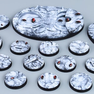 Op de afbeelding: Een set van 14 witte en zwarte ronde en ovale bases met rode accenten. De bases zijn ontworpen met een marmerachtig patroon en zijn perfect voor tabletop-spellen.