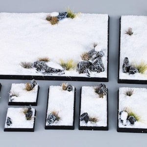 Könnte beinhalten: Ein Set mit 10 schneebedeckten Gelände-Kacheln für Tabletop-Spiele. Die Kacheln verfügen über eine Vielzahl von Texturen und Details, darunter Steine, Gras und Schnee. Die Kacheln sind perfekt, um ein winterliches Schlachtfeld oder eine Landschaft zu schaffen.