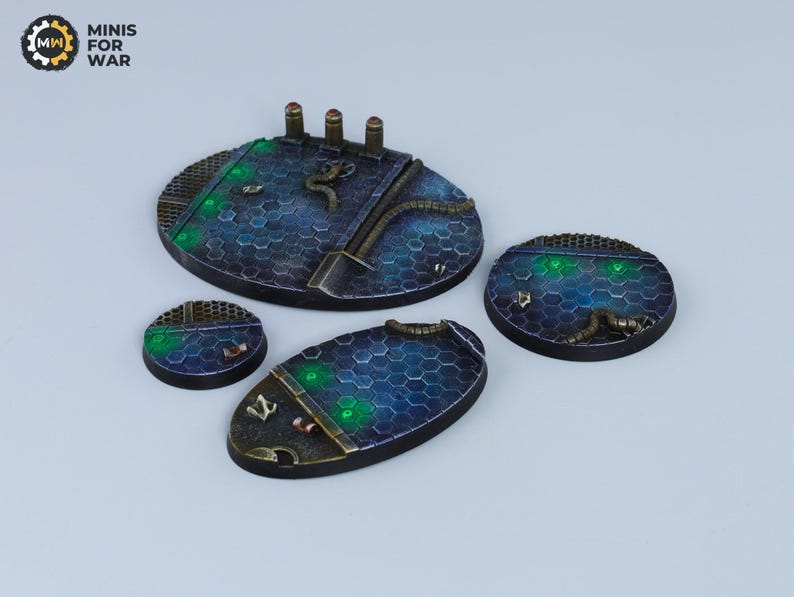 May include: Four round, blue and black, textured, resin gaming bases with green glowing accents. The bases are designed for miniature wargaming.