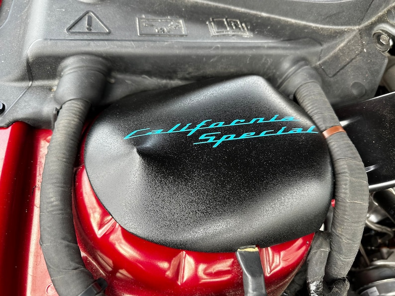 May include: Close-up of a black engine cover with the words "California Special" written in blue lettering.