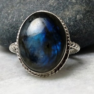 Könnte beinhalten: Ein Silberring mit einem großen ovalen blauen Labradorit-Edelstein, der in einem gedrehten Silberband gefasst ist.