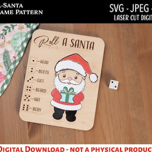 May include: A wooden Roll-A-Santa dice game pattern. The game board features a Santa Claus illustration and the text "Roll A Santa". The game includes a die and instructions for rolling for different Santa features. The text "SVG - JPEG - PDF" is also visible.