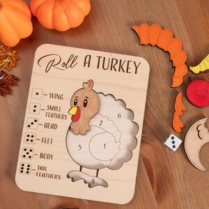 May include: Wooden "Roll a Turkey" game with a turkey outline, dice, and colorful turkey parts. The game board has the text "Roll a Turkey". Includes orange pumpkins and fall leaves.