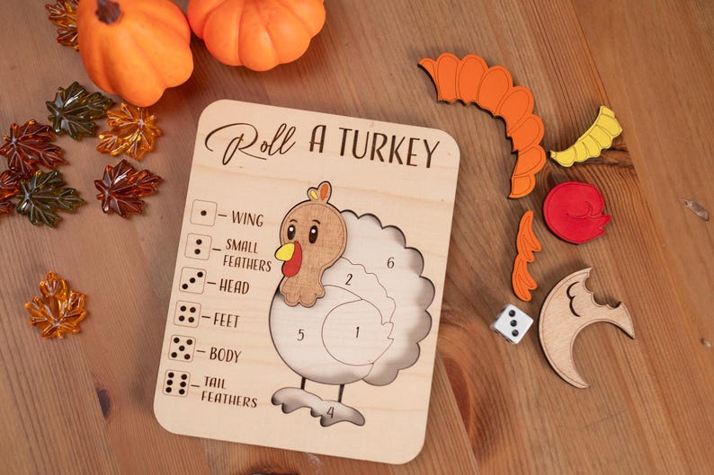 May include: Wooden "Roll a Turkey" game with a turkey outline, dice, and colorful turkey parts. The game board has the text "Roll a Turkey". Includes orange pumpkins and fall leaves.