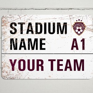 May include: White metal sign with a distressed look. The sign says "Stadium Name A1 Your Team" with a soccer ball logo in the top right corner.