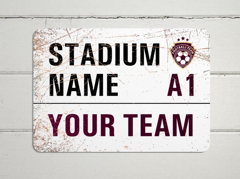 May include: White metal sign with a distressed look. The sign says "Stadium Name A1 Your Team" with a soccer ball logo in the top right corner.