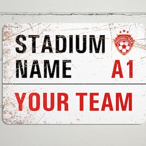 May include: White metal sign with a distressed look. The sign says "Stadium Name A1 Your Team" with a red soccer ball logo in the top right corner.