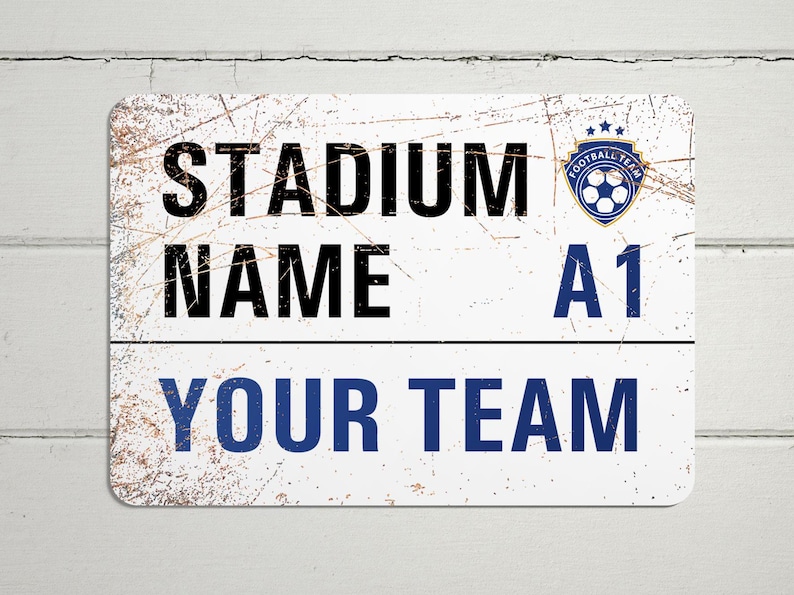 May include: White metal sign with a distressed look. The sign says "Stadium Name A1 Your Team" with a blue soccer ball logo.