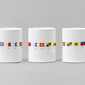 May include: Three white ceramic mugs with nautical signal flags spelling out "CHARLIE". Each mug has a row of flags with the corresponding letter underneath.