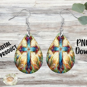 May include: A pair of teardrop-shaped earrings with a stained glass design of a cross. The cross is blue, red, and yellow with a white background. The earrings are silver.