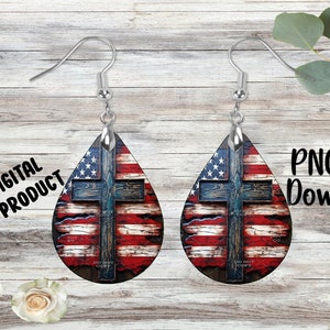 May include: A pair of teardrop-shaped earrings with a distressed American flag design and a wooden cross in the center. The earrings are silver and have a hook closure.