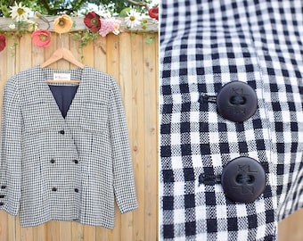 May include: A black and white gingham blazer with a v-neck and double breasted closure. The blazer has two black buttons and two black pockets.