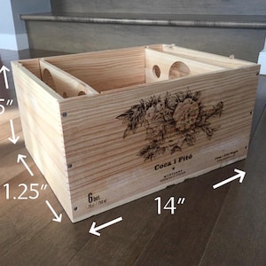 May include: A wooden wine crate with a floral design and the text "Coca i Fito" printed on the front. The crate measures 35.56 cm long, 28.58 cm wide, and 18.41 cm high.