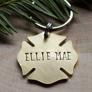 May include: A gold-colored metal firefighter's helmet keychain with the name "Ellie Mae" engraved on it.