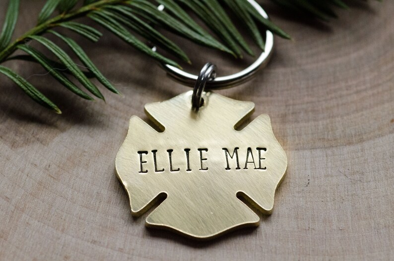May include: A gold-colored metal firefighter's helmet keychain with the name "Ellie Mae" engraved on it.