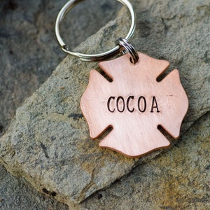 May include: A copper-colored firefighter's helmet-shaped keychain with the name "COCOA" engraved on it.