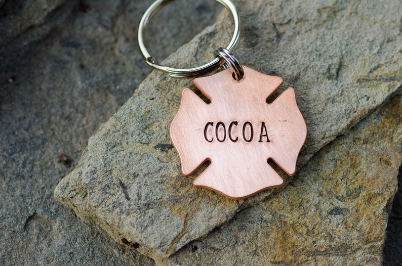 May include: A copper-colored firefighter's helmet-shaped keychain with the name "COCOA" engraved on it.
