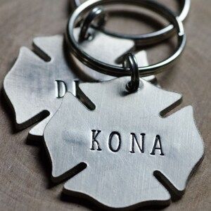 May include: Silver firefighter helmet keychain with the name "KONA" engraved on it.
