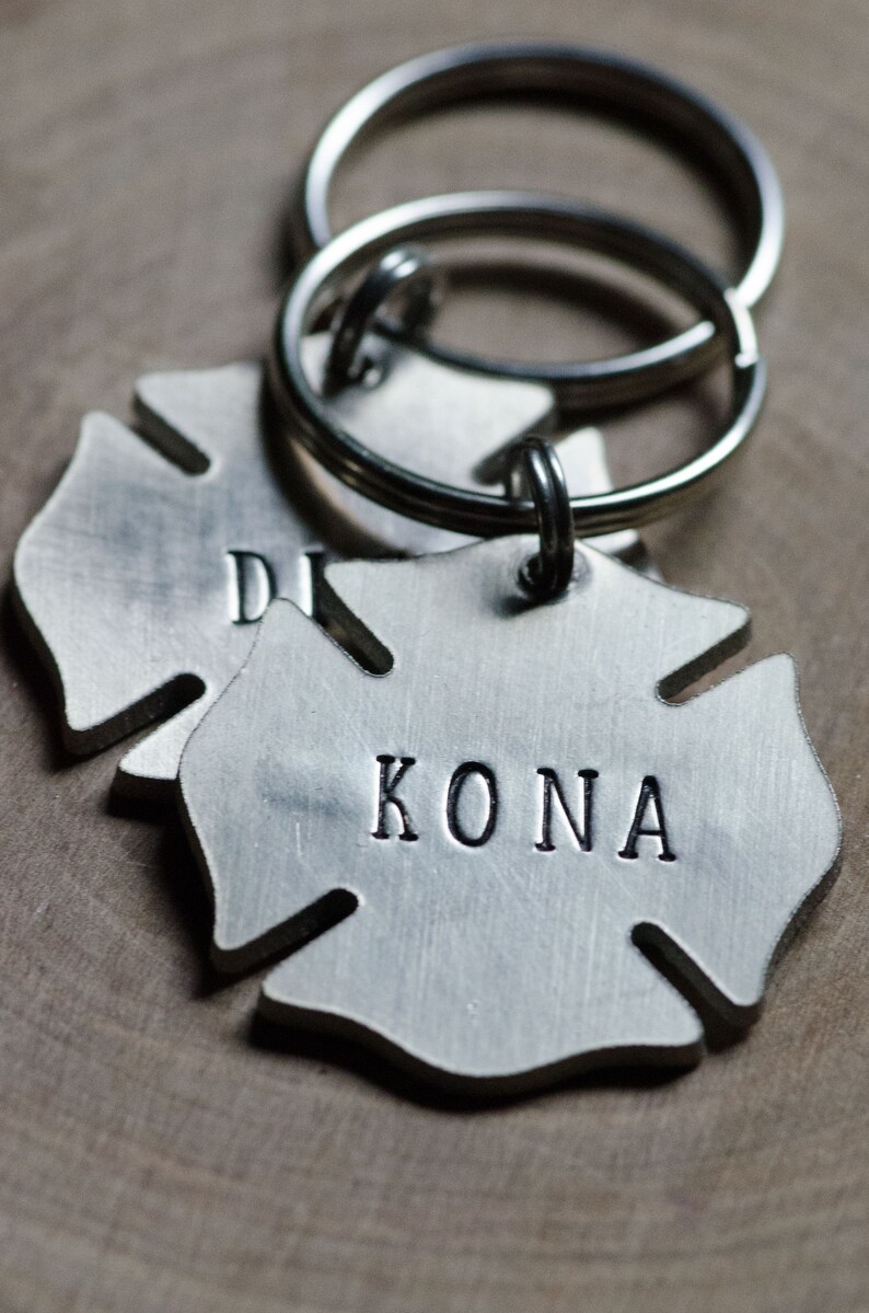 May include: Silver firefighter helmet keychain with the name "KONA" engraved on it.