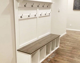 May include: White wooden entryway bench with a shelf and hooks above. The bench has a brown wood top and four cubbies below. The text "Two Willows Market" is visible on the front of the bench.