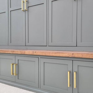 May include: A gray cabinet with a wood top and gold hardware. The cabinet has multiple doors and drawers.