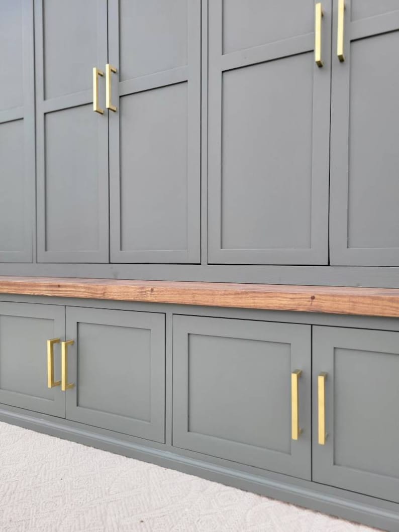 May include: A gray cabinet with a wood top and gold hardware. The cabinet has multiple doors and drawers.