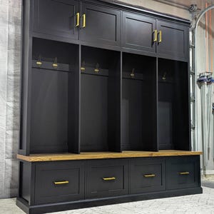 May include: Black wooden entryway bench with three cubbies and a top shelf. The bench has three drawers with gold handles and a wood top. The cubbies have hooks for hanging items.