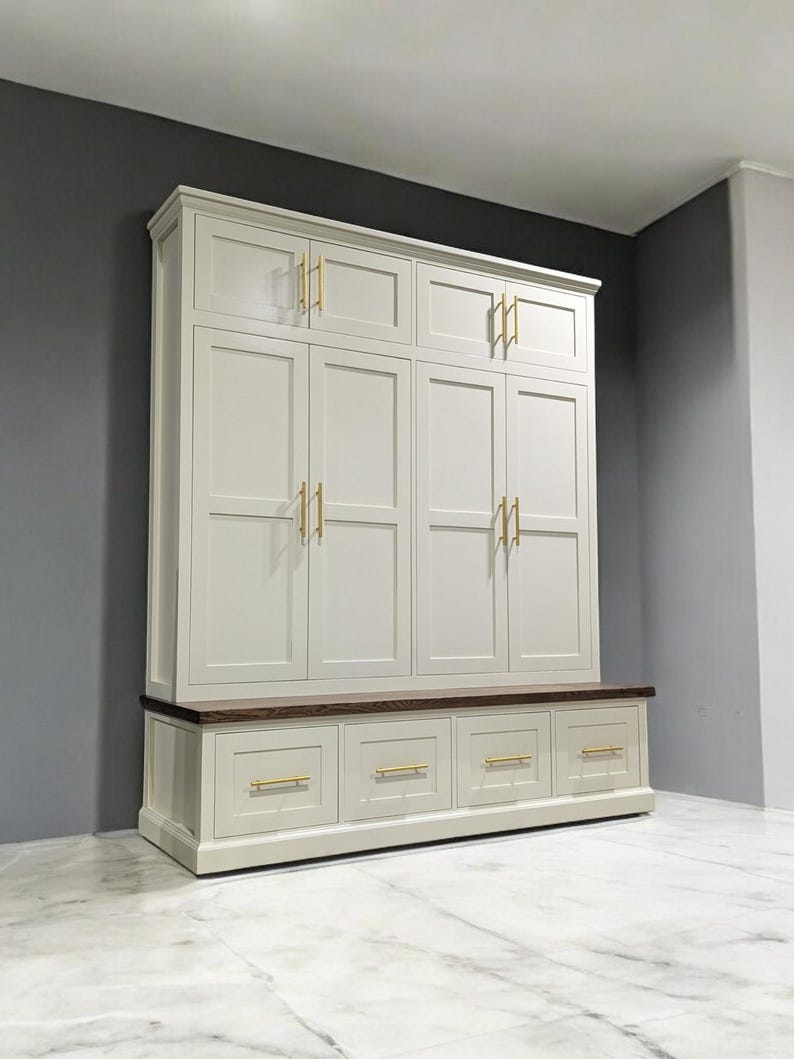 May include: A white cabinet with a wooden top and gold hardware. The cabinet has four doors and four drawers. The cabinet is in a room with a white tiled floor.