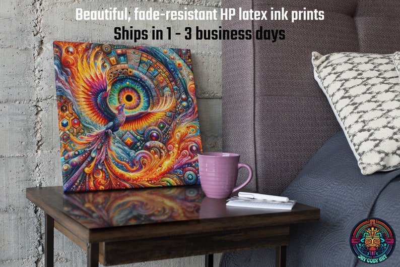 May include: A colorful canvas print featuring a stylized phoenix with a large eye in the center. The print is framed and displayed on a wooden table with a purple mug and a notebook.