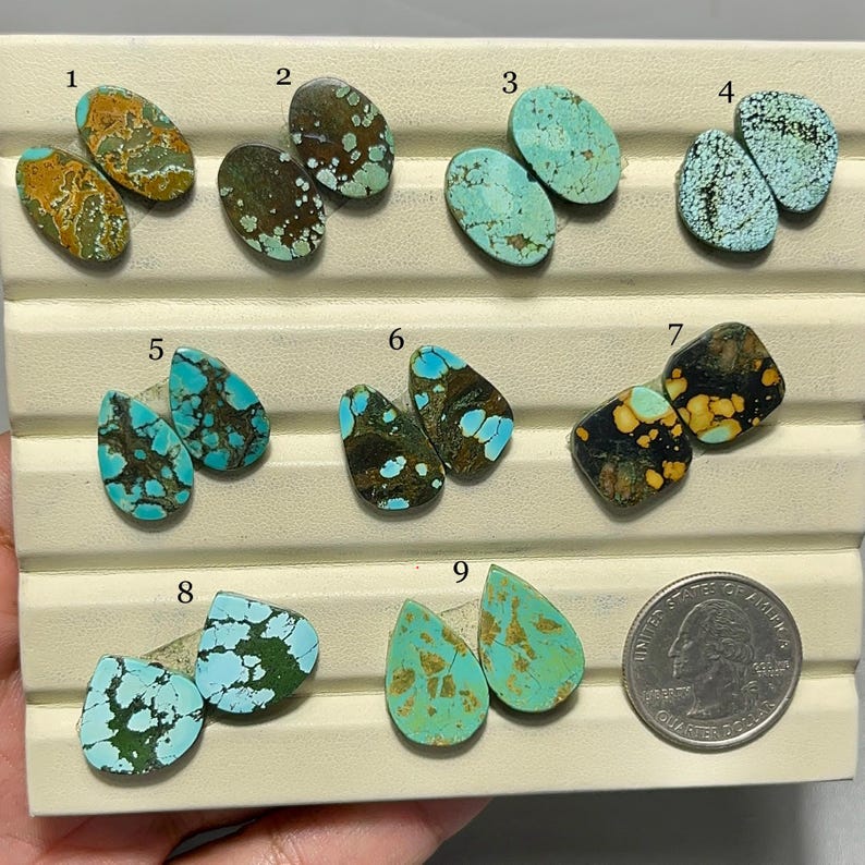May include: A collection of nine pairs of turquoise gemstones in various shapes and colors, including oval, teardrop, and irregular forms. The stones display a range of blue, green, brown, and yellow hues, with unique veining patterns. A US quarter is included for size reference.