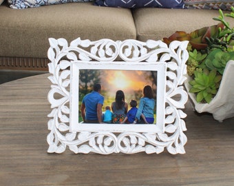 May include: White wooden picture frame with an ornate carved design. The frame holds a photo of a family of five standing in front of a sunset.